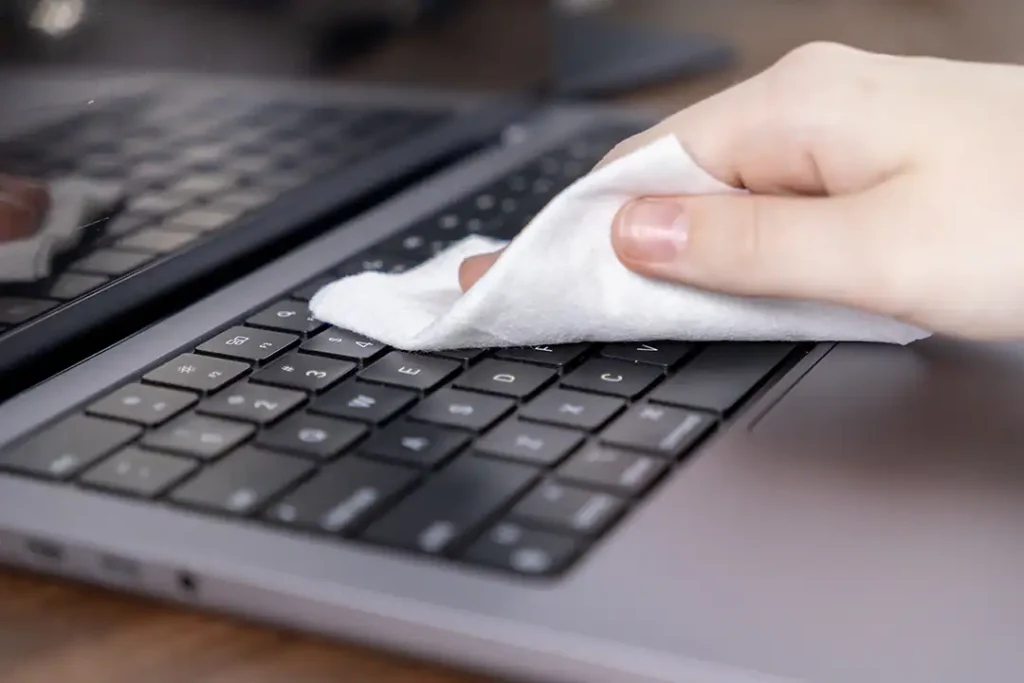 Afbeelding van iemand die zijn laptop schoonmaakt met een doekje