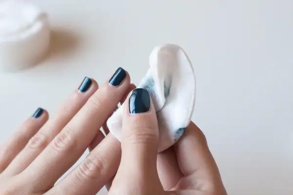 Persoon gebruikt nagellakremover om voorzichtig nagellak te verwijderen van een mooie manicure.