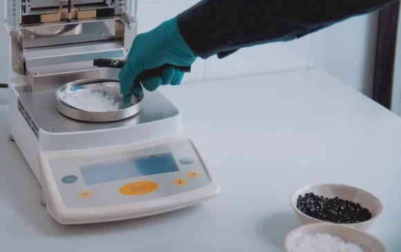 Laboratoriummedewerker weegt chemische grondstoffen op precisiebalans