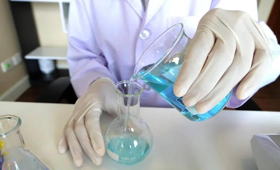 Laborant mengt blauwe chemische vloeistof in maatkolf